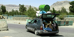 Ein überfülltes Auto in Afghanistan, der Kofferraum steht offen, und auf dem Dach ist ein Ölfass befestigt