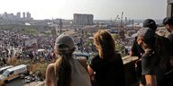 Junge Menschen schauen auf eine zerstörte Lagerhalle am Hafen von Beirut