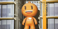 Eine rießige orangfarbene Puppe mit großem Kopf an der Fassade in Hangzhou von Alibaba
