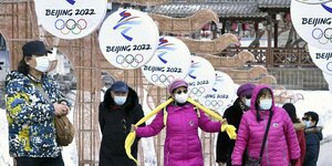 Mehrere Menschen stehen vor Olympia-2022-Peking-Plakaten