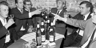 Schwarz-Weiß-Aufnahme von mehreren Männern in einer Gastwirtschaft. Sie trinken sehr viel Wein.