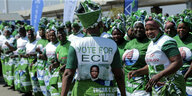 Frauen tragen grüne-weiße Kleider und ein Porträt des Präsidenten Edgar Lungo auf ihrer Kleidung