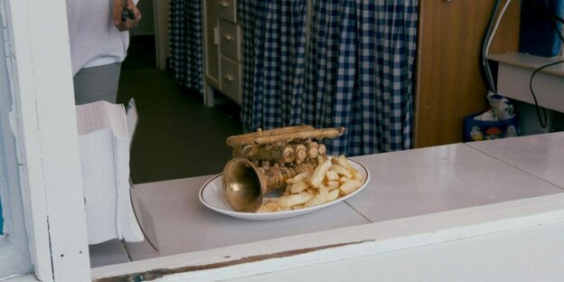 Eine Trompete liegt neben Pommes auf einem weißen Teller