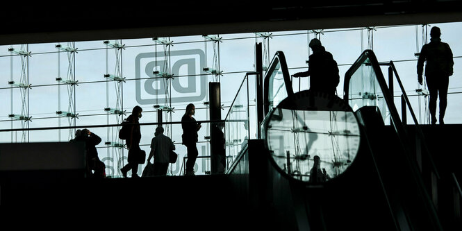 Reisende ziehen Rollkoffer im Berliner Hauptbahnhof hinter sich her