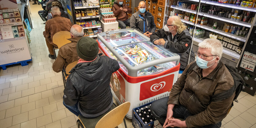 Menschen sitzen auf Stühlen in einer Warteschlange in einem Geschäft