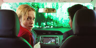 Ein Mann und eine Frau sitzen im Auto über dessen Windschutzscheibe grüne Farbe läuft