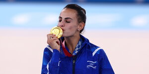 Eine Frau hält ein Plakat hoch, dass die israelische Olympiasiegerin Linoy Ashram zeigt