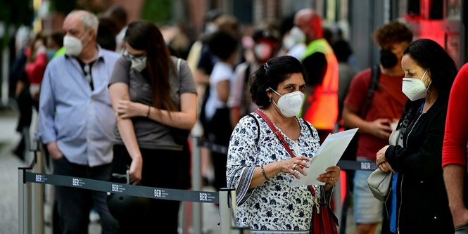 Menschen mit Gesichtsmasken stehen in einer Schlange