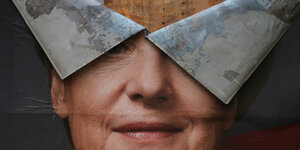 Ein Plakat mit Merkels Gesicht ist von oben eingerissen