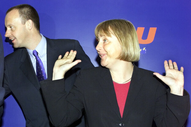 Merkel steht neben Merz, lacht und hält ihre Handflächen nach oben, als würde sie etwas stemmen Merkel steht neben Merz, lacht und hält ihre Handflächen nach oben, als würde sie etwas stemmen