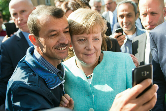 Merkel macht ein Selfie mit einem Geflüchteten