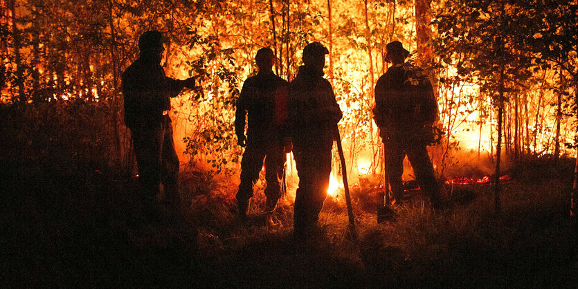 Männer stehen vor hohen Flammen