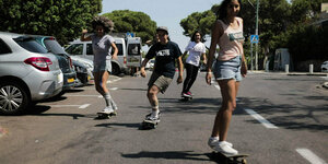 Vier Frauen fahren auf einem Skateboard auf der Straße