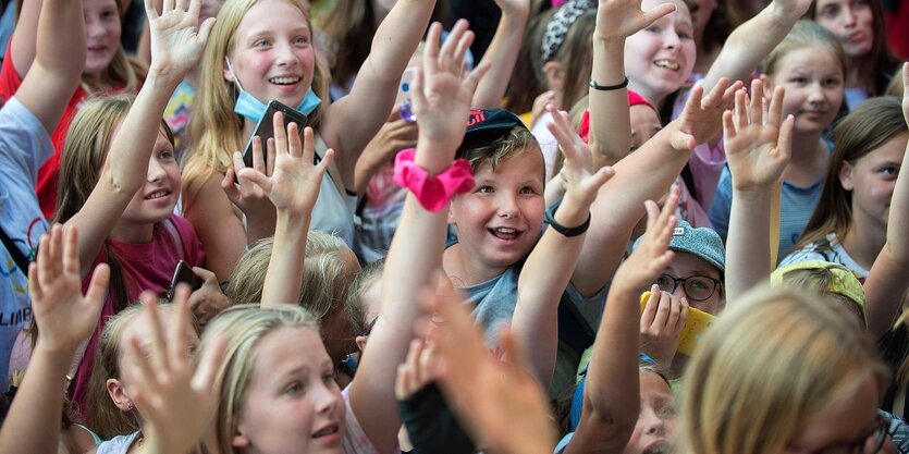 Viele Jugendliche recken die Hände und lachen