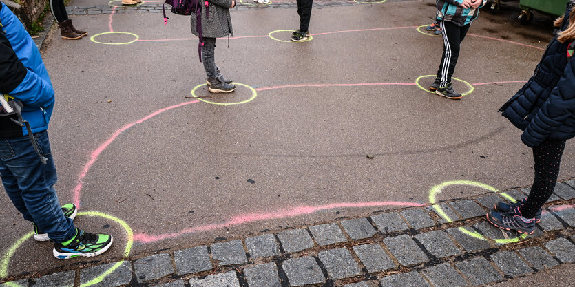 Schüler*innen stellen sich mit Abstand in bunten Kreidekreisen auf.