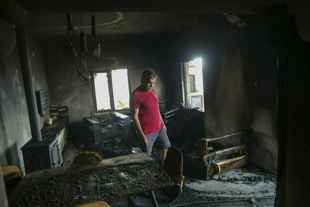 Ein Mann in rotem T-shirt steht in seinem abgebrannten Haus