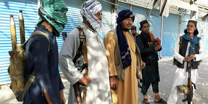 Taliban stehen mit Waffen in einer Straße