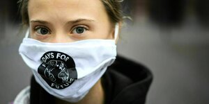Greta Thunberg blcikt einen direkt an und trägt eine Maske mit dem FfF Logo