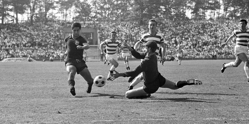 Gerd Müller spielt in einer altrer schwarz-weiß Aufnahme den Toreart des Gegners aus