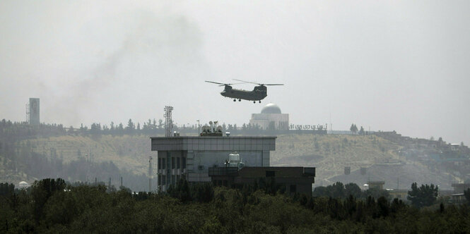 Ein Hubschrauber der USA von Typ Chinook fliegt über der US-Botschaft in Kabul und wirbelt dabei viel Staub auf