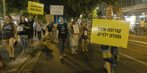 Demonstrationszug in Israel. Eine Frau hät ein Schild hoch: Corona ist keine Kinderkrankheit