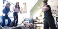 2 Mädchen hopsen auf dem Sofa, eine Mutter schimpft