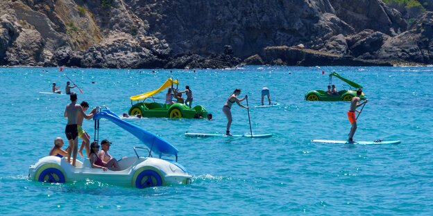 Tretbootautos und Standup Paddler im türkisblauen Wasser