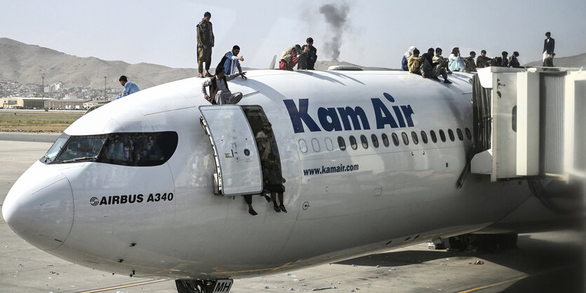 Menschen stehen auf einem geparkten Flugzeug und sitzen in der geöffneten Tür