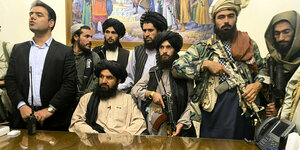 Bewaffnete Taliban mit Turban stehen um den Schreibtisch des Präsidentn Ghani