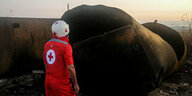 Mitarbeiter des Roten Kreuzes steht vor dem ausgebrannten Tanklastwagen