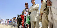 AfghanInnen stehen aufgereiht hinter einer Rolle Stacheldraht