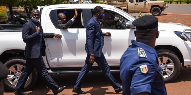 Übergangspräsident Goita winkt aus einem Auto, umgeben von Sicherheitsleuten
