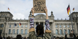 Eine Frau hält vor dem Reichstag ein Poster hoch