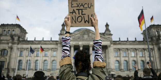 Eine Frau hält vor dem Reichstag ein Poster hoch