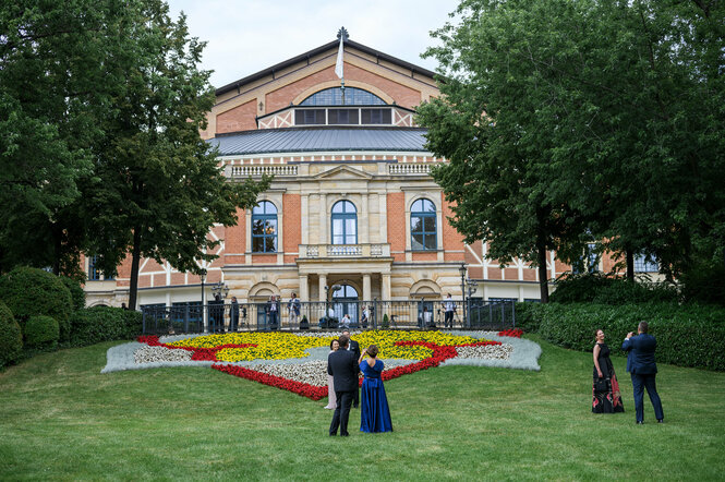 Das Festspielhaus Bayreuth, davor Menschen, die sich fotografieren