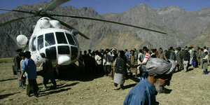 Ein Helikopter landet und um ihn herum stehen afghanische Männer