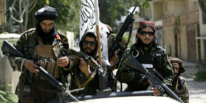 Drei schwerbewaffnete Kämpfer der Taliban mit ihrer Flagge in den Straßen von Kabul