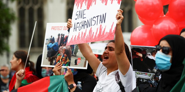 Demonstrierende. Eine Frau hält ein Plakat mit der Aufschrift "Save Afghanistan"