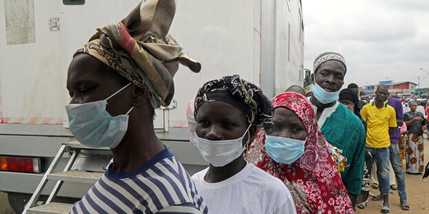 Menschen stehen mit Masken an einer mobilen Impfstation an