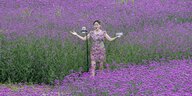 Eine Frau steht mit ihrer Kamera in einem lila Blumenfeld und filmt sich