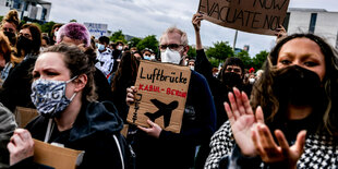 Menschen stehen mit Protestschildern vor dem Reichstag