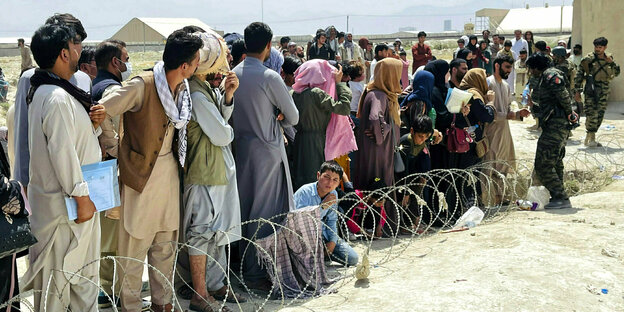 AfghanInnen versammeln sich hinter einem Stacheldraht