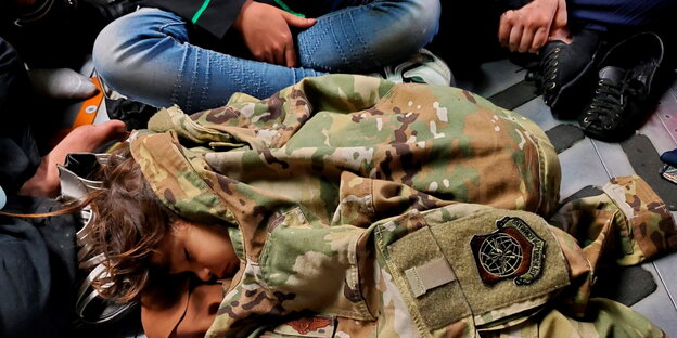 Kind schläft unter einer Uniform im Flugzeug