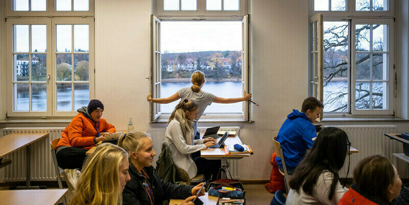 Eine Lehrerin öffnet ein Fenster zum Lüften