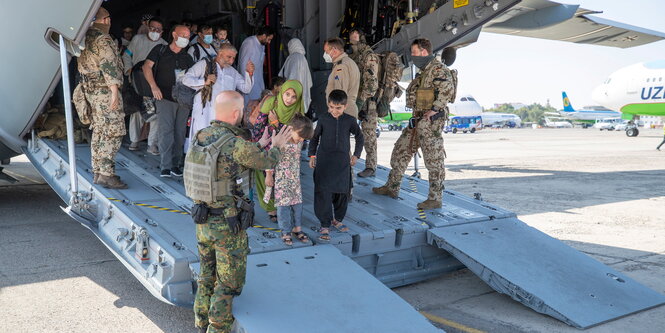 Bundeswehrsoldaten in uniform helfen Menschen dabei, aus einem flugzeug zu steigen. Ganz vorne drei Kinder.