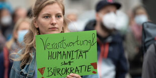 Eine Frau hält auf einer Solidaritätskundgebung ein Schild in die Höhe, auf dem die Forderung nach Humanität steht.