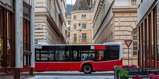 Ein roter Bus fährt durch Wiens Altstadt