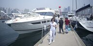 Chinesen gehen auf dem Steg eines Yachhafens