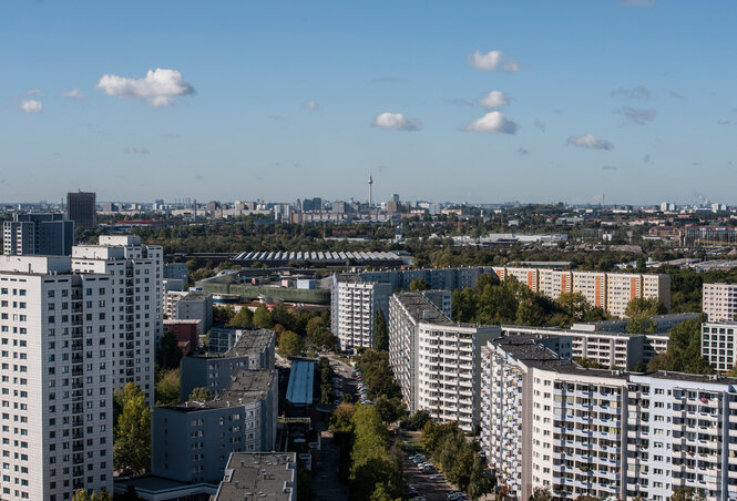 Große Plattenbauten in Marzahn vor der Skyline von Berlin. Sie haben flache Dächer