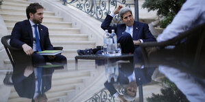 John Kerry sitzt mit zwei weiteren Männern an einem Tisch